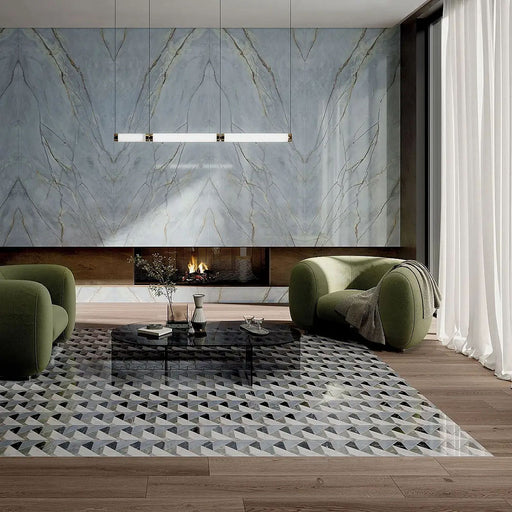 Living room interior featuring Lucca Diamond Tips 3D Décor 60 × 120cm porcelain wall and floor tiles, combining geometric patterned flooring with marble-effect feature walls, styled with olive green lounge chairs, warm wood flooring, and a contemporary fireplace.