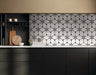 Kitchen interior featuring Lucca Flowers 3D Décor 60 × 120cm porcelain wall and floor tiles, used as a statement splashback with a repeating floral geometric pattern in soft white and black tones, paired with dark cabinetry and warm wood accents.