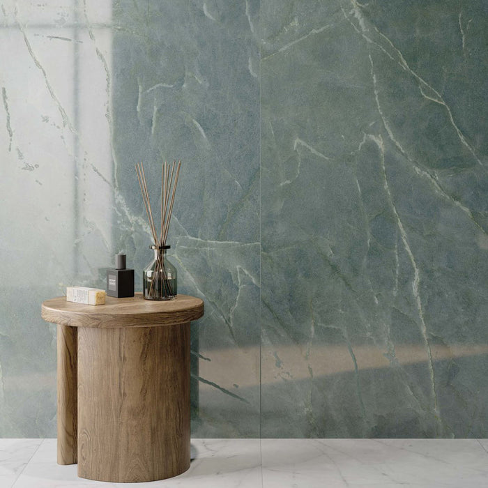 Interior featuring Lucca Ocean Green Lux 3D 60 × 120cm porcelain wall tiles, showcasing rich green marble-effect tones with delicate veining, paired with warm wood furniture and contemporary spa-inspired styling.
