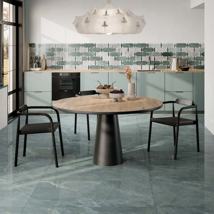 Contemporary kitchen featuring Lucca Ocean Green Lux 3D 60 × 120cm porcelain floor tiles, styled with rich green marble-effect tones, sage cabinetry, wood finishes, and soft modern interior details.