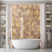 Luxury bathroom interior featuring Lumen Precious Stone Amber 60 × 120cm polished porcelain wall tiles, showcasing rich amber, honey, and smoky stone-inspired tones with dramatic crystalline movement, layered mineral detailing, and a reflective high-gloss finish, paired with a freestanding bath, brushed bronze fittings, fluted wall panelling, and soft ambient lighting.