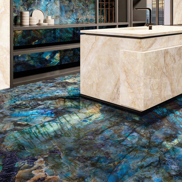 Luxury kitchen interior featuring Lumen Precious Stone Labradorite 60 × 120cm polished porcelain wall and floor tiles, showcasing dramatic blue, teal, and black gemstone-inspired tones with a high-gloss finish, paired with a marble-effect island and dark contemporary cabinetry.