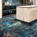 Luxury kitchen interior featuring Lumen Precious Stone Labradorite 60 × 120cm polished porcelain wall and floor tiles, showcasing dramatic blue, teal, and black gemstone-inspired tones with a high-gloss finish, paired with a marble-effect island and dark contemporary cabinetry.