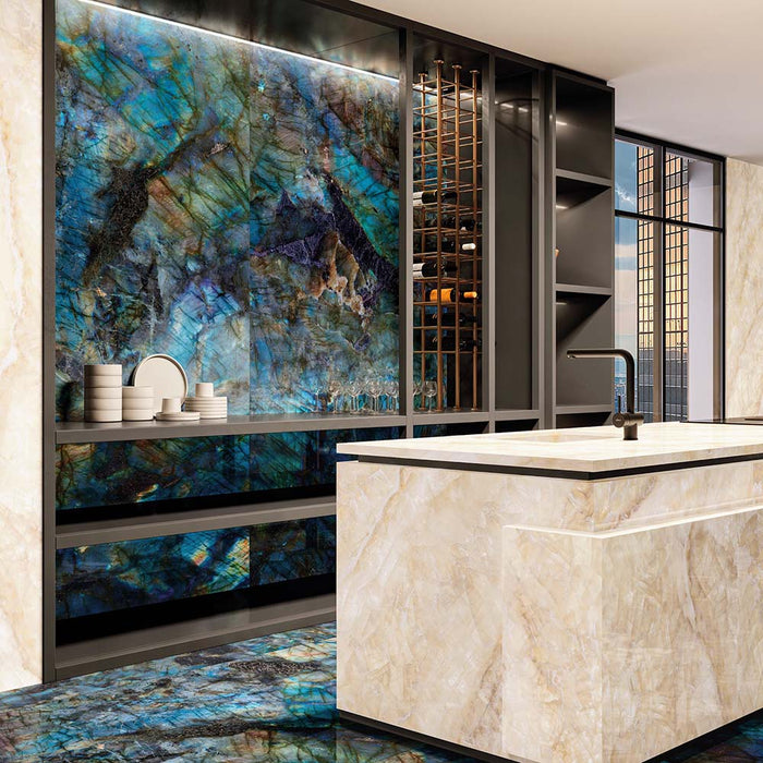 Luxury kitchen interior featuring Lumen Precious Stone Labradorite 60 × 120cm polished porcelain wall and floor tiles, showcasing dramatic blue, teal, and black gemstone-inspired tones with a high-gloss finish, paired with a marble-effect island and dark contemporary cabinetry.