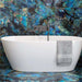 Bathroom interior featuring Lumen Precious Stone Labradorite 60 × 120cm polished porcelain wall and floor tiles, showcasing vivid blue, teal, and charcoal gemstone-inspired detailing with an iridescent high-gloss finish, paired with a freestanding white bath and brushed metal fittings for a dramatic luxury look.