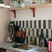Kitchen interior featuring Zellige Malachite Green and Zellige Oyster 6.5x20cm Moroccan-style brick tiles installed vertically in a striped splashback, styled with brass tap, wooden shelving, and greenery for a warm, contemporary look.