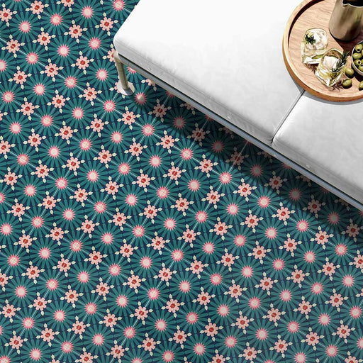 Living room floor featuring Fez Festival 20x20cm Moroccan-style porcelain tiles, showcasing a bold multicolour geometric pattern in teal, pink and coral tones, styled with a white upholstered bench and a wooden side table for a vibrant, contemporary look.