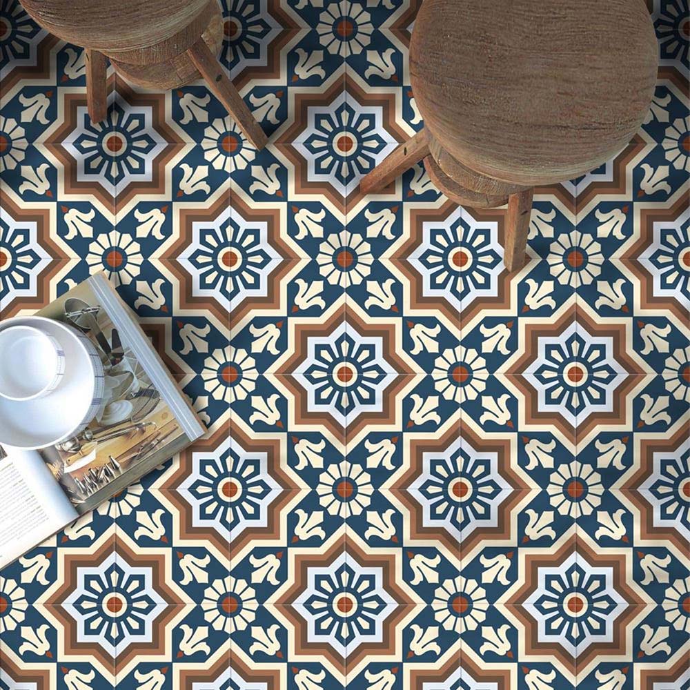 Living space featuring Balthazar Grand 20×20cm Moroccan-style porcelain floor tiles, showcasing an intricate geometric pattern in blue, brown and cream tones, styled with rustic wooden stools and warm natural textures for a bold, characterful finish.