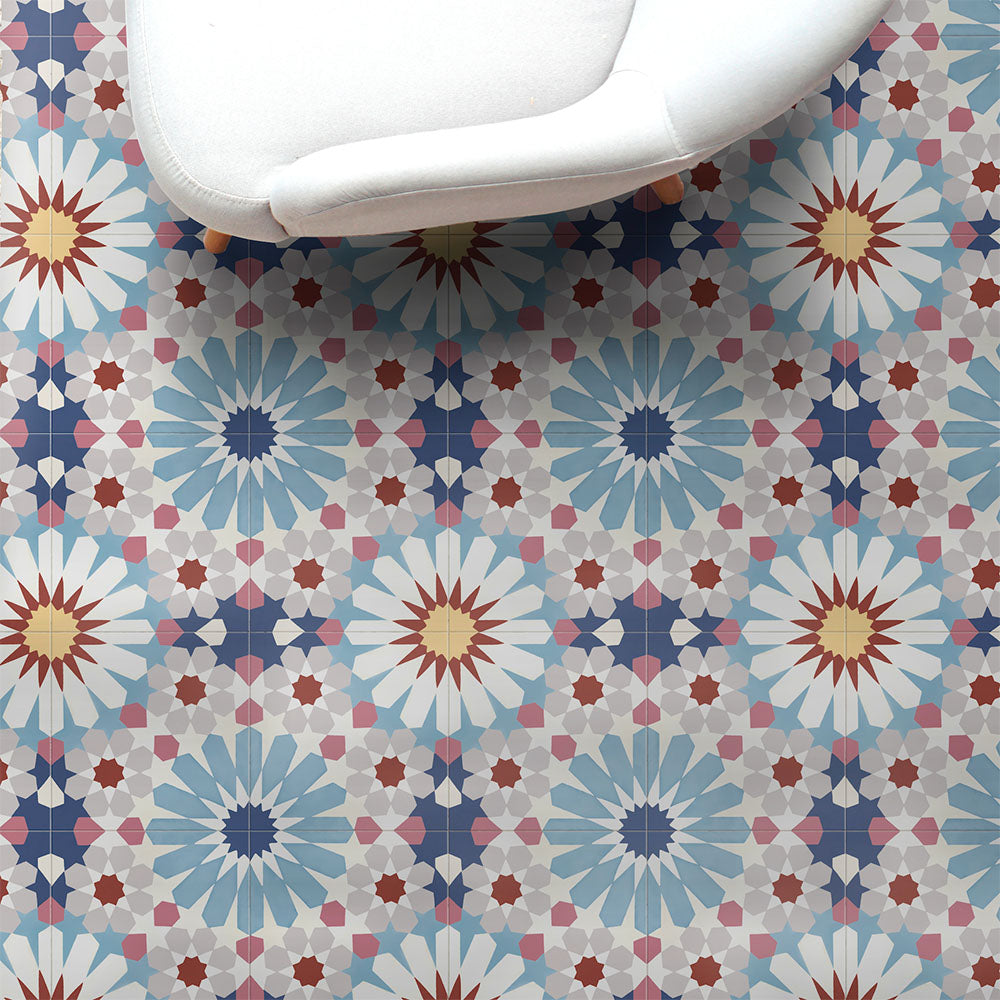 Fez Fiera Moroccan style porcelain floor tiles featuring a repeating geometric pattern in blue, terracotta, grey and cream, styled beneath a white accent chair