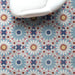 Fez Fiera Moroccan style porcelain floor tiles featuring a repeating geometric pattern in blue, terracotta, grey and cream, styled beneath a white accent chair