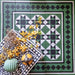 Styled flat lay of Greenbrook Manor anti-slip encaustic Victorian-style porcelain tiles, showcasing a green, black and white geometric pattern with decorative border tiles, accented with dried flowers and ceramic accessories.