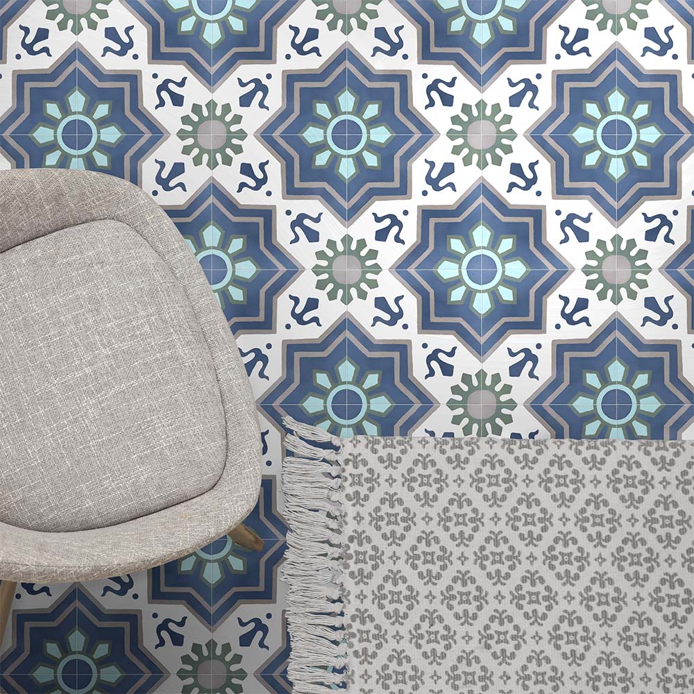 Living space featuring Balthazar Blue 20×20cm Moroccan-style porcelain floor tiles, showcasing a striking geometric pattern in layered blue, teal and soft grey tones, styled with a neutral armchair and textured rug for a balanced, contemporary look.
