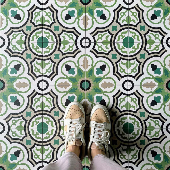 Flat-lay setting featuring London Streets Bond Street 20x20cm Victorian Moroccan style floor tiles, showcasing the repeating geometric pattern in green, black and cream tones, styled with trainers for a lifestyle tile display.