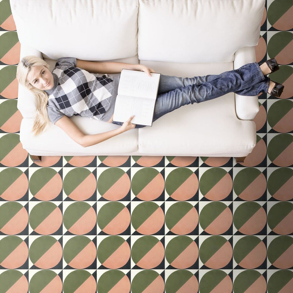 Living room styled with Abstract Moon Patterned Tiles in a 20x20cm format, laid as a bold geometric floor design beneath a white sofa. The repeating circular pattern in muted green and soft blush tones creates a contemporary, artistic look, adding colour and visual interest to this modern interior setting.