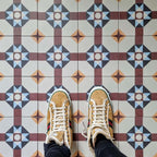 Flat-lay setting featuring London Streets Berlin Street 20x20cm Victorian Moroccan style floor tiles, showcasing the repeating geometric star pattern in burgundy, soft blue and cream tones, styled with trainers for a lifestyle tile display.