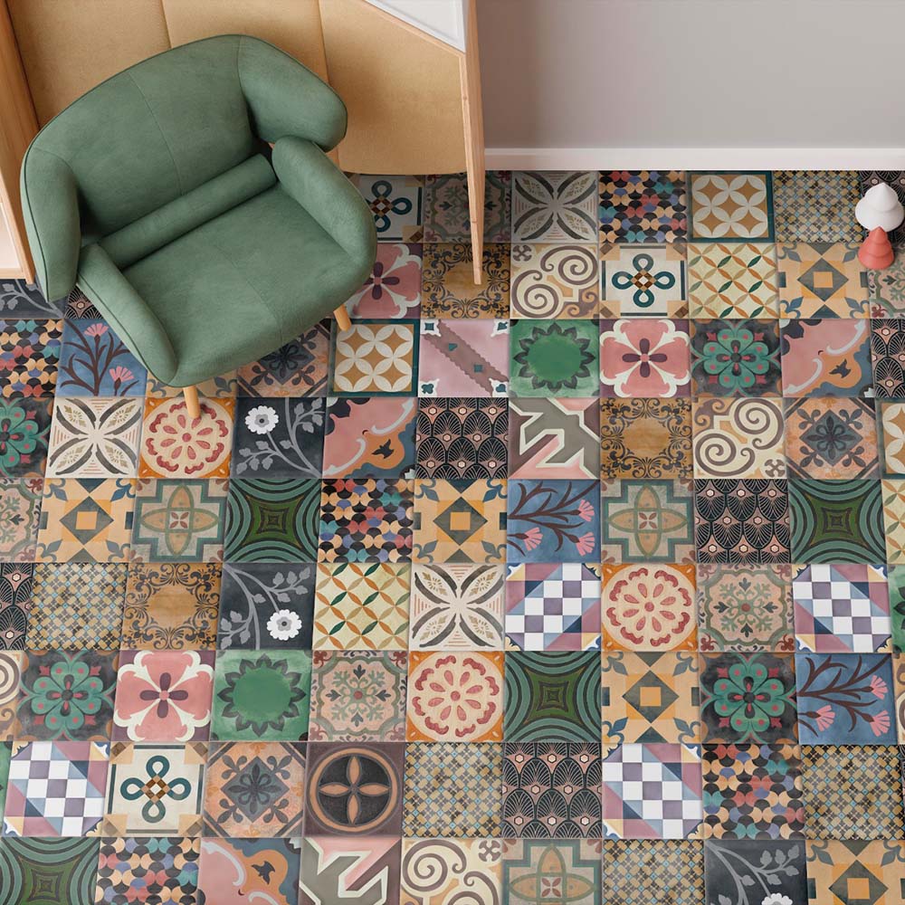 Interior floor featuring Cuba Patchwork Moroccan-style porcelain tiles in a 20×20cm square format, laid in a mixed patchwork design combining geometric, floral and traditional motifs in rich earthy, green, blue and terracotta tones, styled with a green armchair to showcase the tile’s eclectic, decorative character.