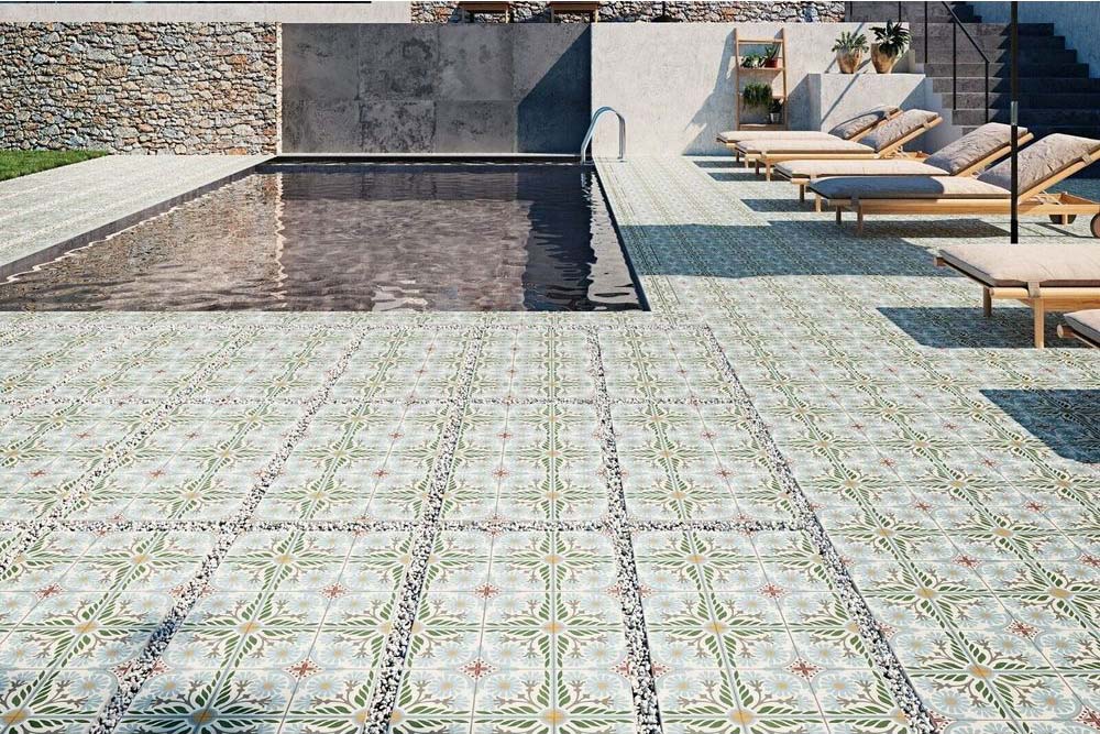 Modern outdoor pool area featuring Mediterraneo Olbia 2cm patterned outdoor slabs 50 × 100cm, showcasing a faded Mediterranean-inspired design in soft green and neutral tones, paired with sun loungers and contemporary architecture.