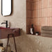 Contemporary bathroom featuring Melange Sand concrete-effect wall and floor tiles 60 × 60cm, showcasing warm sand-toned concrete-inspired detailing with subtle texture, paired with terrazzo accents, blush pink features, and minimalist décor.