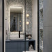 Modern bathroom featuring Melody Pop Blue 60cm x 120cm terrazzo effect porcelain feature wall tiles, paired with large-format grey wall tiles, a blue floating vanity, black brassware and illuminated mirror.
