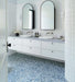 Minimalist bathroom featuring Melody POP Terrazzo Blue 60 × 60cm terrazzo-effect porcelain tiles, showcasing soft white stone fragments across a muted blue base, paired with crisp white surfaces, black fixtures, and clean contemporary styling.