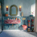 Eclectic bathroom featuring Melody POP Terrazzo Blue 60 × 60cm terrazzo-effect porcelain floor tiles, showcasing soft white stone fragments scattered across a muted blue base, paired with glossy blue wall tiles, a dramatic red marble-effect basin, and playful contemporary styling.