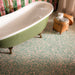 Bathroom featuring Melody POP Terrazzo Green 60 × 60cm terrazzo-effect porcelain floor tiles, showcasing a playful green and pink speckled design, paired with striped glossy wall tiles, floral wallpaper, and a sage green freestanding bath for a bold maximalist-inspired interior.