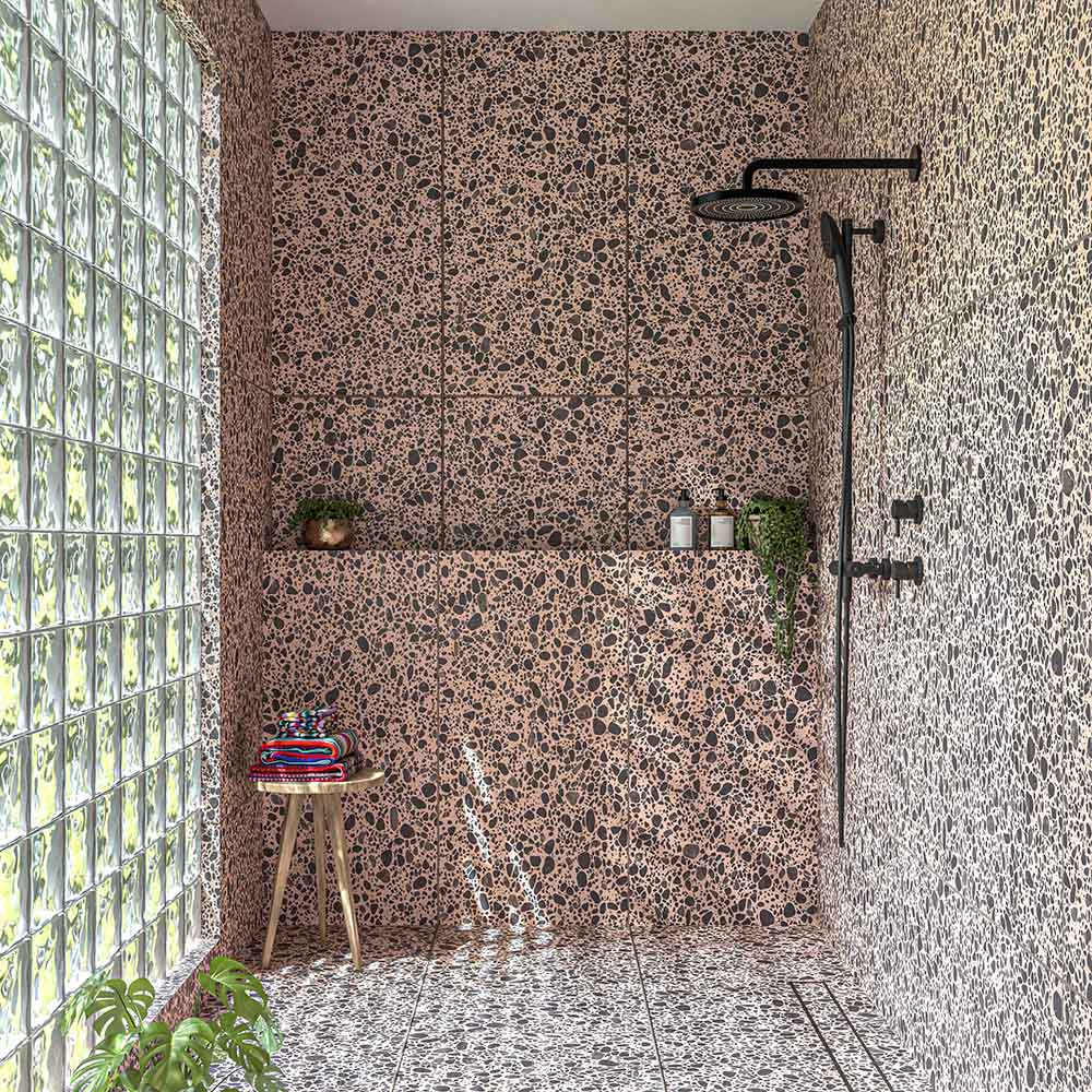 Walk-in shower featuring Melody POP Terrazzo Pink 60cm x 120cm terrazzo effect wall and floor tiles, with pink and black detailing, black shower fittings and a glass block wall.