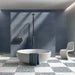 Contemporary bathroom featuring Melody POP Terrazzo White 60 × 60cm terrazzo-effect porcelain floor tiles, laid in a bold blue and white chequerboard design and paired with deep blue wall tiles, a freestanding bath, and minimalist fittings for a striking modern interior.