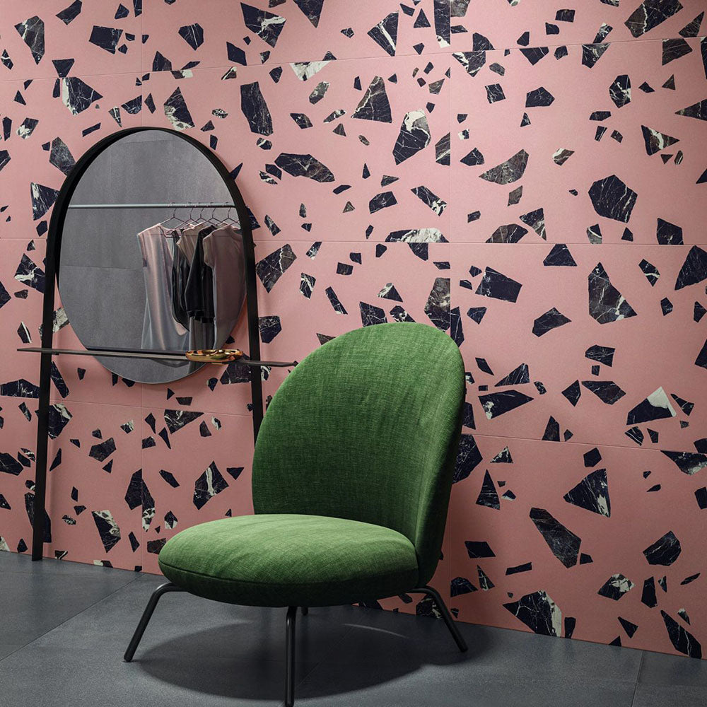 Contemporary interior featuring Melody ROCK Terrazzo Pink 60 × 60cm porcelain wall tiles, designed with oversized black marble-effect fragments set against a soft pink background, creating a bold terrazzo-inspired statement paired with modern furniture and deep charcoal flooring.