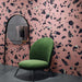 Contemporary interior featuring Melody ROCK Terrazzo Pink 60 × 60cm porcelain wall tiles, designed with oversized black marble-effect fragments set against a soft pink background, creating a bold terrazzo-inspired statement paired with modern furniture and deep charcoal flooring.