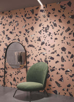 Contemporary interior featuring Melody ROCK Terrazzo Pink 60 × 60cm porcelain wall tiles, designed with oversized black marble-effect fragments set against a soft pink background, creating a bold terrazzo-inspired statement paired with modern furniture and deep charcoal flooring.