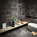 Lifestyle image of Monzo Stone Nite 30x60cm dark stone-effect porcelain wall and floor tiles, featuring rich charcoal tones, subtle veining and varied natural stone-inspired texture, styled within a contemporary bathroom with matte black accents and minimalist décor.