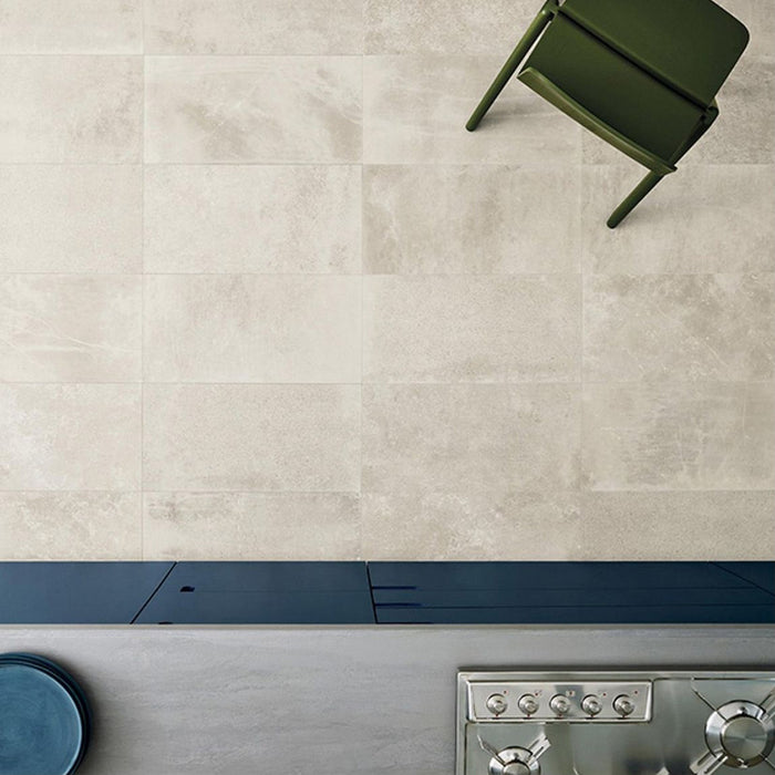 Kitchen featuring Monzo Stone Sand 30x60cm stone-effect porcelain wall tiles in warm beige tones, styled with dark blue kitchen cabinetry, stainless steel appliances, and subtle natural-style veining for a contemporary interior look.