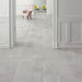 Interior featuring Monzo Stone Silver 30x60cm stone-effect porcelain floor tiles in soft silver-grey tones, styled with white panelled walls, pastel accent chairs, and subtle natural-style veining for a contemporary interior look.