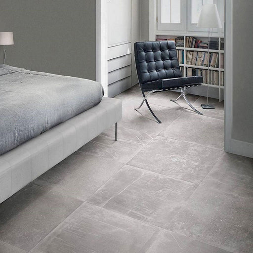 Bedroom featuring Monzo Stone Titanium 60x60cm stone-effect porcelain floor tiles in soft grey tones, styled with modern furniture, neutral interiors, black leather seating, and subtle natural-style veining.