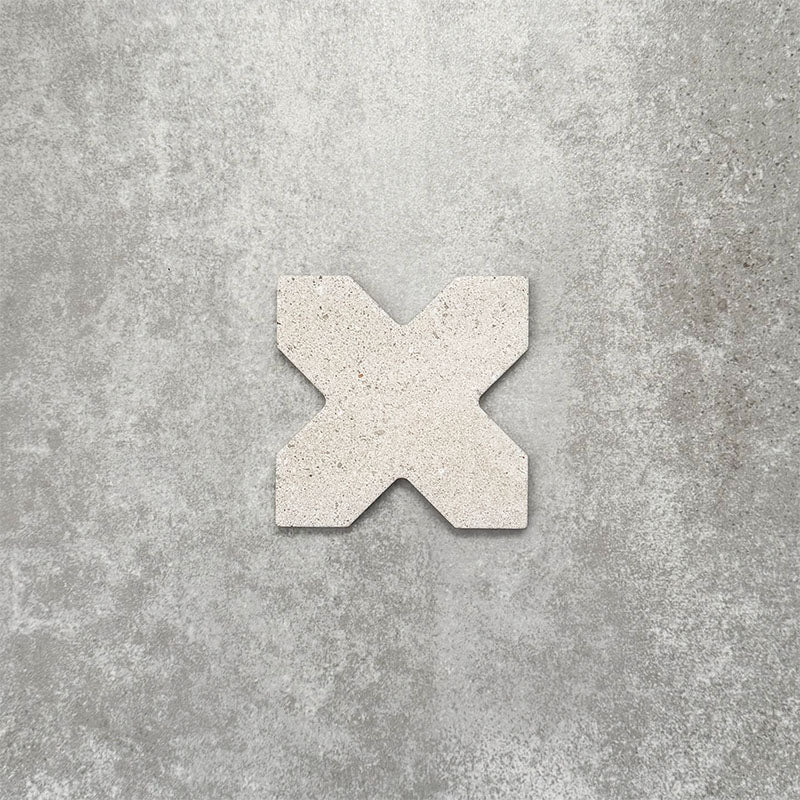 Close-up of Muscat Avorio Rocks Cross wall and floor tile, showcasing a distinctive geometric cross shape, soft ivory tones, subtle speckled detailing and a textured stone-effect finish.