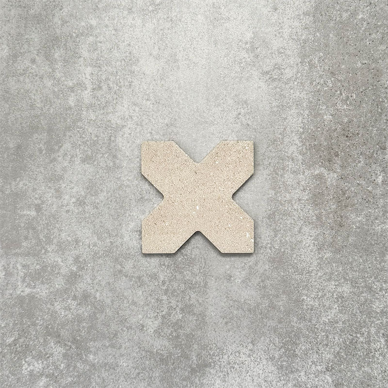 Close-up of Muscat Sands Cross wall and floor tile, showcasing a distinctive geometric cross shape, warm sandy beige tones, subtle speckled detailing and a matt finish.