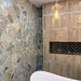 Bathroom featuring Museo Warm Stone Matt 60x120cm porcelain wall tiles, showcasing a bold marble effect design in warm beige, ivory and grey tones, complemented by textured neutral wall tiles, brass accents and a contemporary freestanding bath.