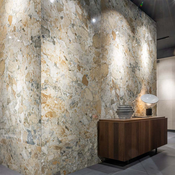Interior featuring Museo Warm Stone Polished 60x120cm porcelain tiles, showcasing a striking marble effect design with warm beige, grey and ivory tones, paired with dark wood furniture and contemporary decorative lighting.