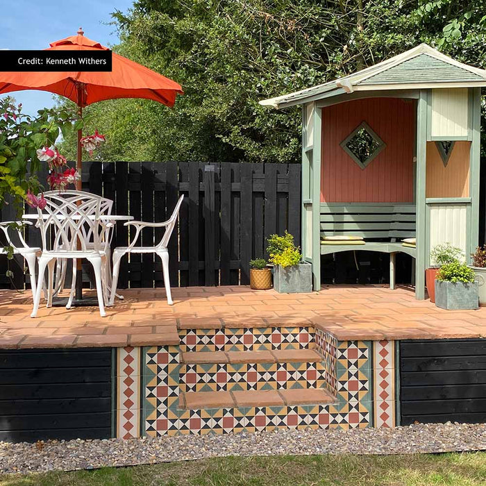Outdoor garden steps featuring Newton Manor Side/Border 20cm x 20cm Victorian style tiles, creating a decorative geometric border in red, cream, black and green alongside coordinating patterned tiles.