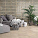 Living room featuring Ourika Emerald Green Moroccan style decorative porcelain wall tiles, showcasing an intricate geometric floral pattern in soft emerald green, beige and cream tones, paired with stone effect floor tiles, natural planting and relaxed contemporary furnishings for a warm, Mediterranean-inspired interior.