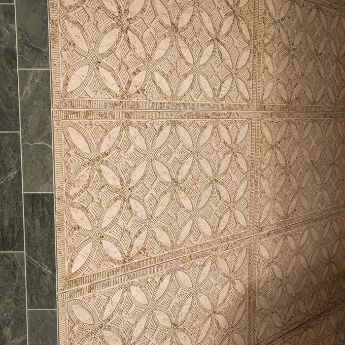 Close-up of Ourika Sandy Beach Moroccan-style porcelain wall tiles, featuring intricate geometric and floral patterns in warm beige and sandy brown tones, with decorative textured detailing, paired with dark green marble wall tiles.