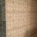 Close-up of Ourika Sandy Beach Moroccan-style porcelain wall tiles, featuring intricate geometric and floral patterns in warm beige and sandy brown tones, with decorative textured detailing, paired with dark green marble wall tiles.
