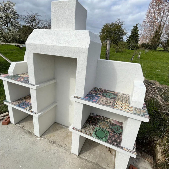 Outdoor fireplace featuring Cuba Patchwork Moroccan-style porcelain tiles in a 20×20cm square format, used across shelving and surfaces in a mixed patchwork design with geometric and traditional motifs in earthy, green, blue and terracotta tones, creating a bold decorative finish for an outdoor space.