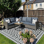 Outdoor seating area featuring Dorset Tile Black & White Victorian-style porcelain floor tiles in a 25 × 25cm format, laid in a bold geometric pattern with a decorative border, styled with woven garden furniture, lantern lighting and planting to create a classic yet contemporary garden space.