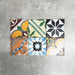 Fayrouz Mini Patchwork 15×15cm Moroccan-style porcelain tiles displayed as a mixed patchwork layout, showcasing a vibrant collection of geometric and floral designs in green, blue, pink, mustard, terracotta and neutral tones.