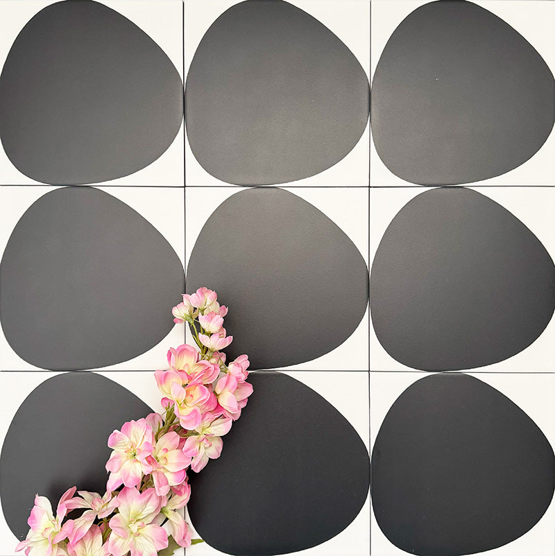 Pebbles Reversed Black 20x20cm porcelain Moroccan-style tiles featuring bold abstract black shapes on a soft white background, designed to create striking statement walls and contemporary patterned interiors.