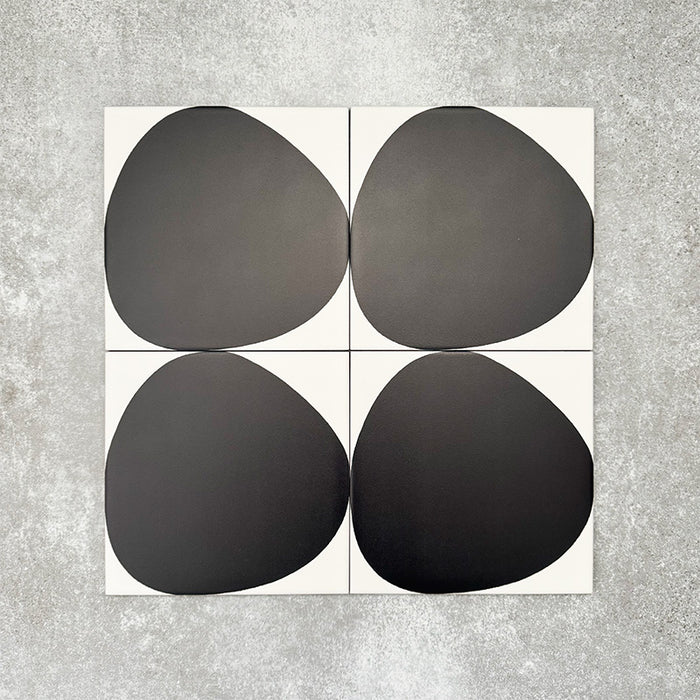 Pebbles Reversed Black 20x20cm porcelain Moroccan-style tiles featuring bold abstract black shapes on a soft white background, designed to create striking statement walls and contemporary patterned interiors.