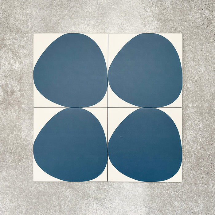 Pebbles Reversed Blue 20x20cm porcelain Moroccan-style tiles featuring bold organic blue shapes on a soft white background, designed to create playful statement walls and contemporary patterned interiors.