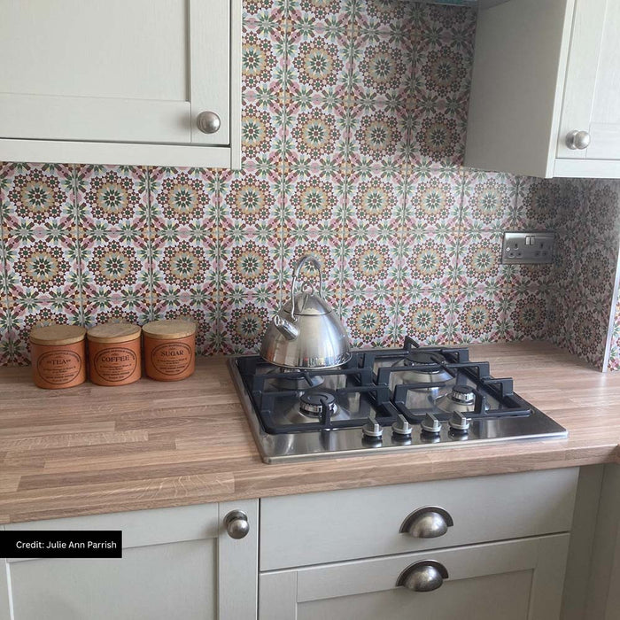 Kitchen featuring Persia Mini Flowers 15x15cm patterned wall tiles used as a splashback, showcasing soft pink, sage green and warm neutral geometric floral motifs, paired with shaker cabinets, oak-effect worktops and a stainless steel gas hob.